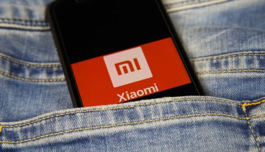 Viersen, Almanya - 1 Mart. 2021: Mavi kot pantolonlu Çinli Xiaomi cep telefonu şirketinin logo harfleriyle akıllı telefon ekranının kapatılması