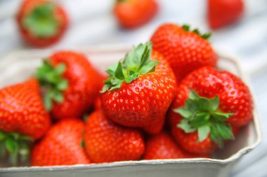 Alman çiftçi pazarından taze taze çilek karton kutu içinde beyaz ahşap masanın üzerinde.
