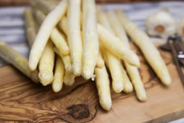 Ahşap masanın üzerinde pişmemiş çiğ beyaz kuşkonmaz mızrakları.