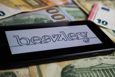 Viersen, Germany - March 1. 2021: Closeup of smartphone with logo lettering of beazley insurance company on paper money currency