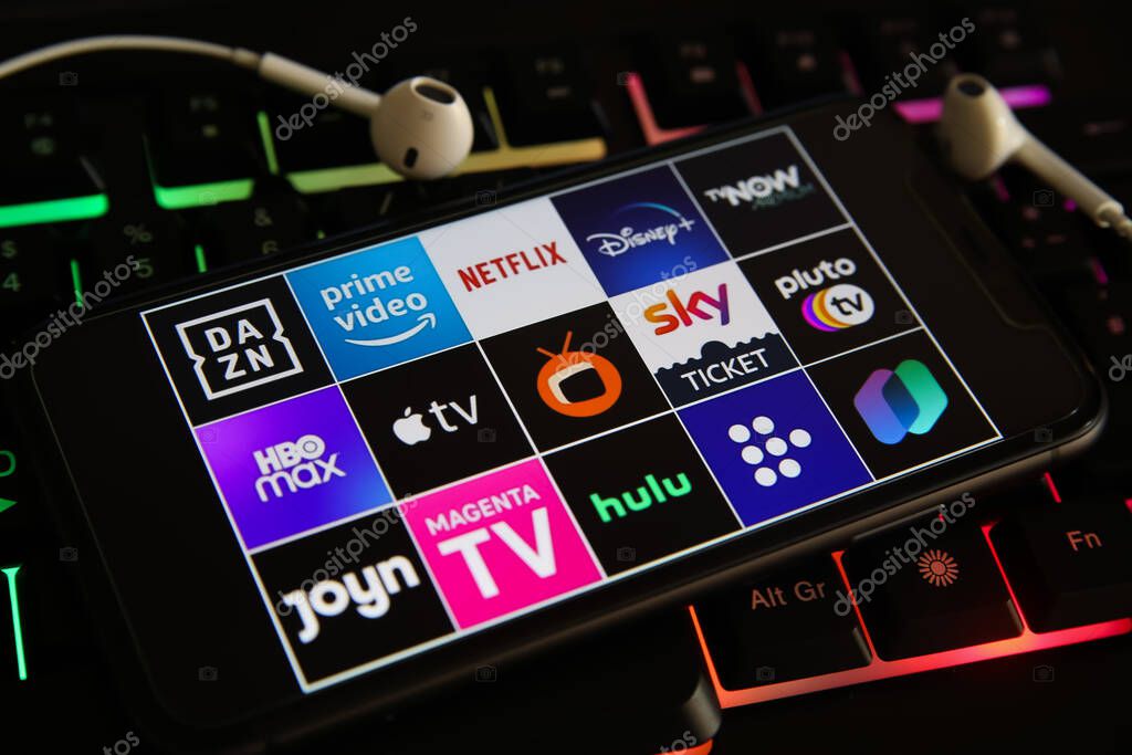 Viersen, Germany - March 1. 2021: Closeup of mobile phone screen with logo lettering of various tv movie streaming services on laptop keyboard