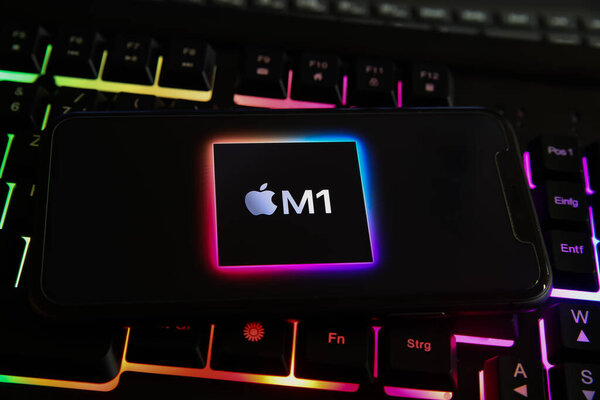 Viersen, Germany - May 8. 2021: Closeup of smartphone with logo lettering of apple M1 processor cpu on computer keyboard