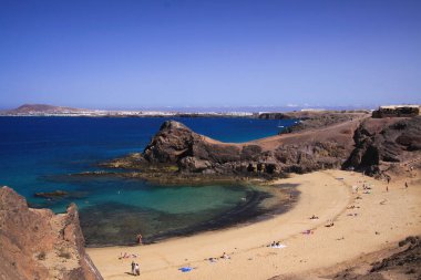 Dik uçurumdan gözlerden uzak mavi göl kumsalına az sayıda insan ve beyaz köy geçmişi - Playa Papagayo, Playa Blanca - Lanzarote