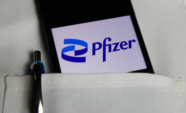 Viersen, Almanya - 9 Mayıs. 2021: Cep telefonu ekranının kapatılması ve Pfizer eczacılık şirketinin logosu beyaz doktor önlüğünün cebinde.