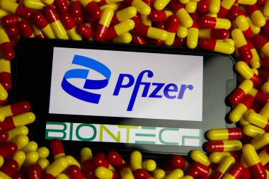 Viersen, Almanya - 9 Mayıs. 2021: Cep telefonu ekranının kapatılması ve Pfizer ve Biontech eczacılık şirketlerinin ilaç yığını üzerindeki logosu (Pfizer kelimesinin merkezine odaklan)