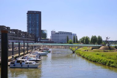Venlo, Hollanda - 9 Haziran. 2021: Maas Nehri üzerinden Hollanda 'nın silueti üzerinde limanı ve tekneleri olan yaz manzarası