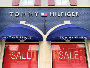 Roermond, Hollanda - 1 Temmuz. 2021: Vitrinde Tommy Hilfiger ve kırmızı satış tabelalarının logosu olan mağaza cephesine bak (üst harf merkezine odaklan)