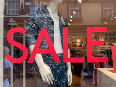 Roermond, Hollanda - 1 Temmuz. 2021: Sahte arka plan ve kırmızı metin satışıyla moda mağazasının vitrininde görüntüle