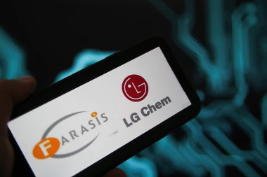 Viersen, Almanya - 9 Mayıs. 2021: Telefon ekranının kapatılması, pil üreticisi Farasis Energy ve Ig Chem 'in logo harfleri, bulanık güç devresi arkaplanı