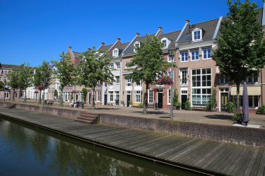 Helmond, Hollanda - 10 Temmuz. 2021: Mavi gökyüzü olan geleneksel Hollandalı evleri su kanalından izleyin