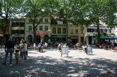 Kempen (NRW) - Almanya - 1 Temmuz. 2021: Yazın çınar ağaçlarının gölgesinde insanların oturduğu restoranlar ve eski evlerin olduğu pazar yerinde manzara