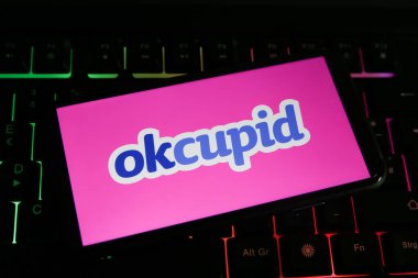 Viersen, Almanya - 1 Haziran. 2021: Cep telefonu ekranının kapatılması ve bilgisayar klavyesinde okcupid çevrimiçi flört servisi logosu
