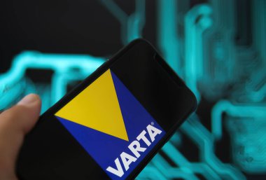 Viersen, Almanya - 9 Mayıs. 2021: Varta batarya üreticisinin logo harfleriyle telefon ekranının kapatılması, bulanık güç devresi arkaplanı