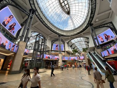 Oberhausen (Centro), Almanya - 9 Temmuz. 2021: Yürüyen merdivenler, cam kubbe ve dijital reklam ekranlarının doğal ışığı ile parlak fütüristik modern alışveriş merkezi salonunun içine bakın