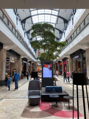 Oberhausen (Centro), Almanya - 9 Temmuz. 2021: Ağaç ile modern alışveriş merkezinin içine bakın, telefon yükleme istasyonu ile rahatlatıcı alan