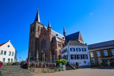 Neer (Limburg), Hollanda - 9 Temmuz. 2021: Ortaçağ kilise ve restoran binasını bulutsuz mavi yaz gökyüzüne karşı görmek