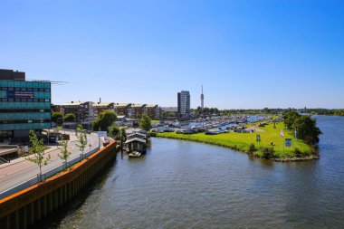 Roermond (Marina Oolderhuske), Hollanda - 9 Temmuz. 2021: Limanda mavi yaz gökyüzü, şehir manzarası ve nehir manzarasına karşı motorlu tekneler ve yelkenli yatlarla görüntüleme