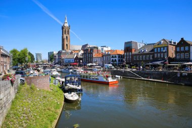 Roermond, Hollanda - 9 Temmuz. 2021: Şehir manzaralı yoğun Hollanda su kanalına ve mavi yaz gökyüzüne karşı eski kilise kulesine bakın