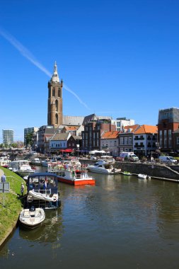 Roermond, Hollanda - 9 Temmuz. 2021: Şehir manzaralı yoğun Hollanda su kanalına ve mavi yaz gökyüzüne karşı eski kilise kulesine bakın