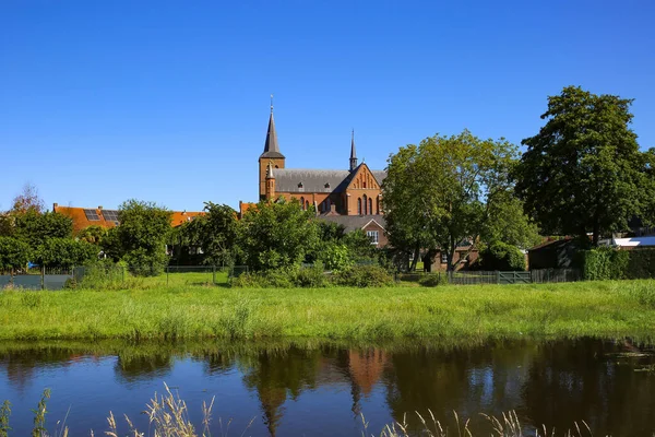 荷兰尼耶 一个有着中世纪古老教堂的小杜奇田园诗村 在蓝云夏日的天空下俯瞰河流和绿茵的牧场 — 图库照片