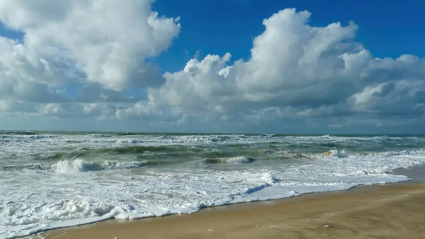 Fransız Atlantik Okyanusu 'nda kumsaldaki dalgaların üzerinden mavi gökyüzü bulutların üzerinden Soulac-sur-mer, Bretagne, Fransa