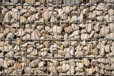 Metal bir kafesin içinde uzanan pek çok kaba taşın arka planı ve dokusu bir duvar oluşturuyor.