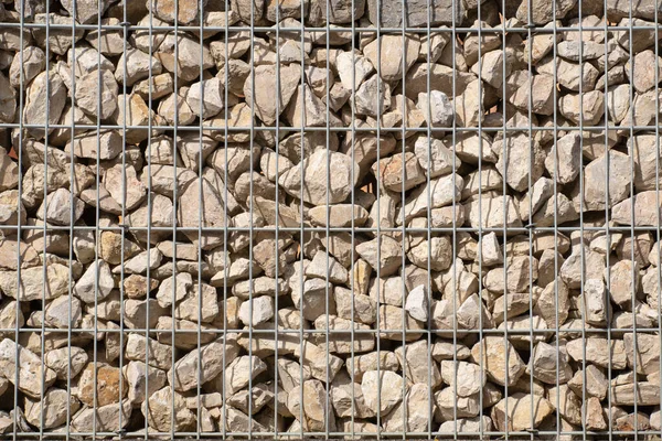 Metal bir kafesin içinde uzanan pek çok kaba taşın arka planı ve dokusu bir duvar oluşturuyor.