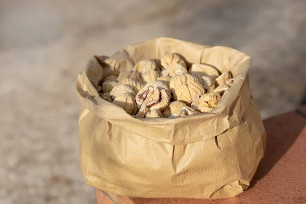 There are a lot of dried chestnuts in a paper bag that is in the open air