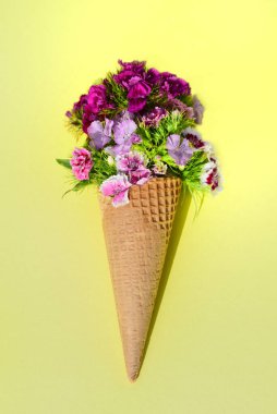 Sarı arka planda dondurma külahıyla sakin bir hayat. Çantada bir sürü renkli çiçek var, sözde bıyık, dondurma yerine waffle 'ın içinde.