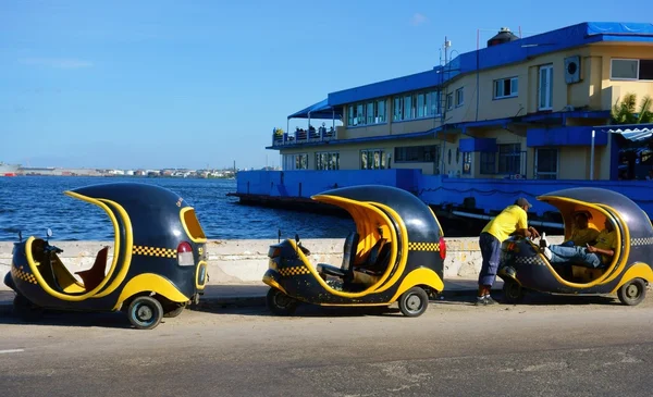 Three Cocotaxis and their drivers in Havana harbor Royalty Free Stock Images