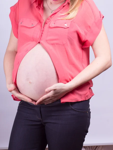Barriga de mulher grávida com vermelho — Fotografia de Stock