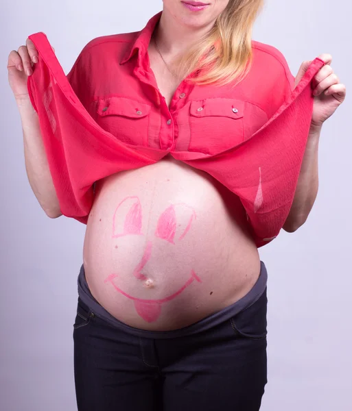 Painted  happy smiley face on the belly of pregnant girl — Stock Photo, Image