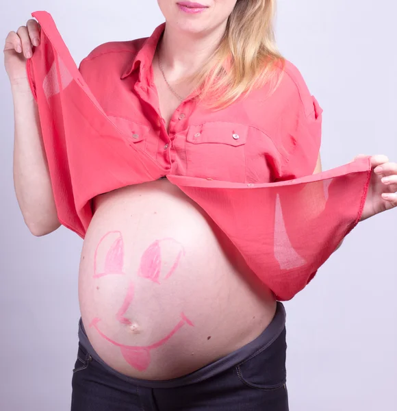 Painted  happy smiley face on the belly of pregnant girl — Stock Photo, Image