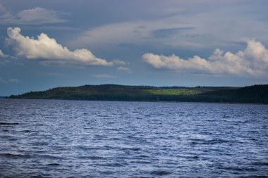 yaz gününde yeşil ağaçlar ile nehir kıyısında. Bulutlarla mavi gökyüzü