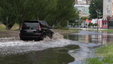 Cherkassy, Ukrayna - 5 Haziran 2016: araba sürüş su dolu bir yolda ağır yağmur, Cherkassy kaynaklanan bir sel sırasında.