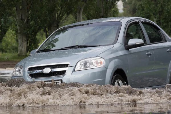 Carros dirigindo em uma estrada inundada durante uma inundação causada após a chuva forte — Fotografia de Stock