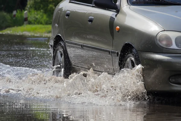 Автомобілі, що їздять по затопленій дорозі під час повені, викликаної сильним дощем — стокове фото