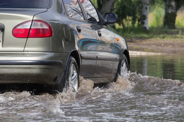 Automóviles que conducen por una carretera inundada durante una inundación causada por fuertes lluvias — Foto de Stock