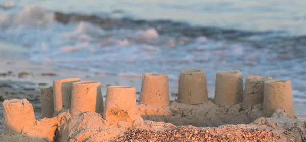 在沙滩蓝海的南岸建造了有塔楼的房子沙堡 — 图库照片