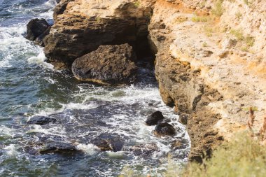 Deniz dalgaları su sıçramalarıyla kayalara çarpıyor.