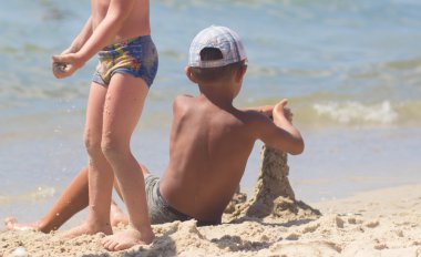 Kumlu kumsalın mavi denizinin güney kıyısında kuleleri olan bir kumdan kale inşa ettim.