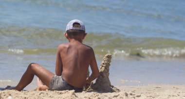 Kumlu kumsalın mavi denizinin güney kıyısında kuleleri olan bir kumdan kale inşa ettim.