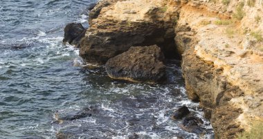 Deniz dalgaları su sıçramalarıyla kayalara çarpıyor.