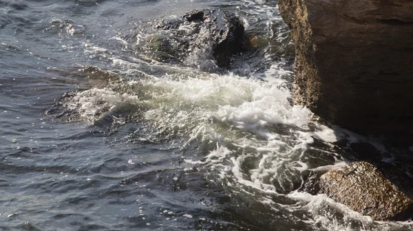 Havsvågor bryter på stenar med stänk — Stockfoto