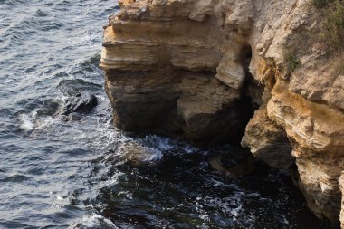 Deniz dalgaları su sıçramalarıyla kayalara çarpıyor..