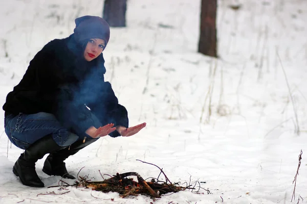 Dziewczyna ogrzewa jego ręce nad ogniem zimą — Zdjęcie stockowe