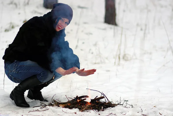 Dziewczyna ogrzewa jego ręce nad ogniem zimą — Zdjęcie stockowe