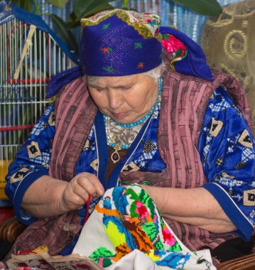 yaşlı kadın onun Kanaviçe işi nakış tarafından oturur