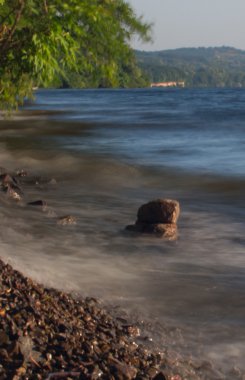 Deniz dalgaları plajda kayaya çarpıyor.