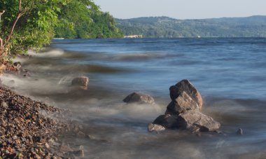 Deniz dalgaları plajda kayaya çarpıyor.